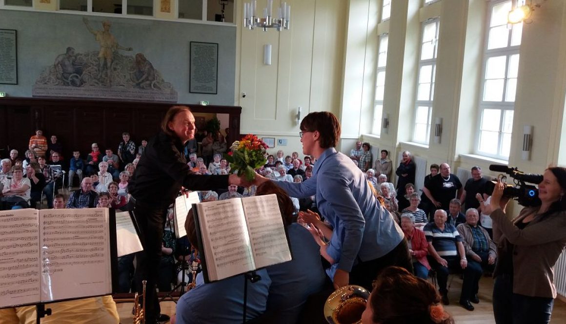Stadtmusikdirektor überreicht Blumenstrauß an Muttis im Orchester. Foto: JBO